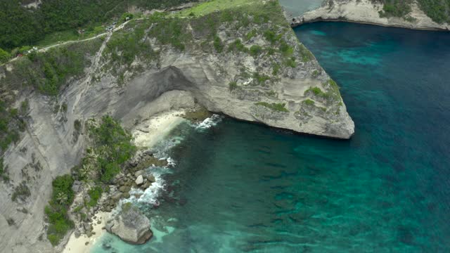 空中淘金在陡峭的岩石形成的热带绿松石水域，沙滩，溅起的波浪，和珊瑚礁-努沙佩尼达和龙目岛，巴厘岛视频素材