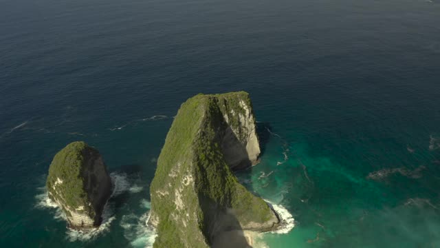 空中拍摄陡峭的海滩悬崖，突出到绿松石蓝色的海水和旋转的海浪和沙滩，阳光普照的海滩-努沙佩尼达&龙目岛，巴厘岛视频素材