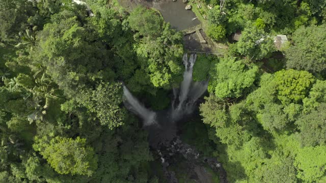 空中旋转进入三瀑布包围着欲望植物覆盖的悬崖和明亮的阳光反射的树梢-努沙佩尼达和龙目岛，巴厘岛视频素材