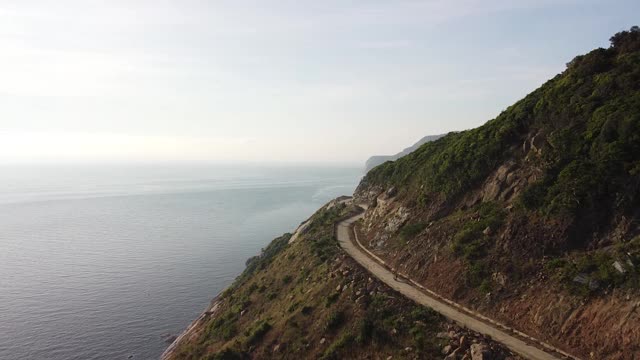 航拍:夏日热带岛屿上的悬崖边弯弯曲曲的道路视频素材