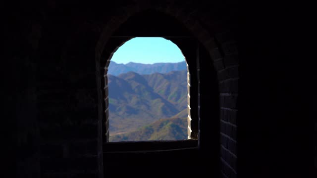 斯坦尼康镜头拍摄的中国长城，在山的一侧上升在一个开始下降。摄像头通过瞭望塔的通道，显示了从墙上的窗户看到的景色视频素材