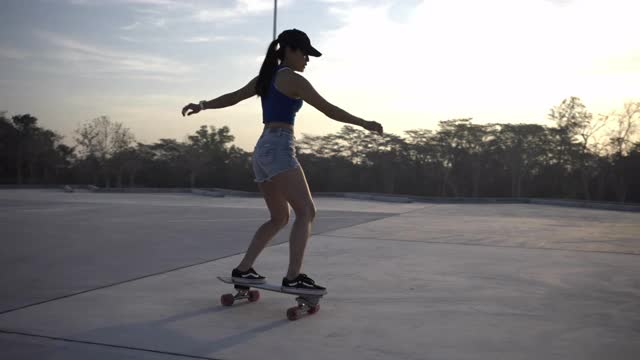 亚洲妇女在美丽的夏天在户外冲浪或滑冰。快乐的年轻女子早上在公园玩冲浪滑冰。视频素材