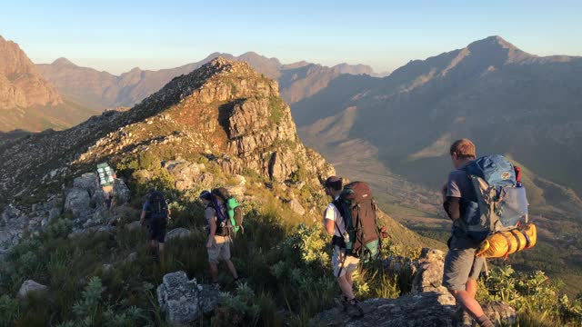 夕阳西下时在山顶上徒步旅行的一群人视频素材