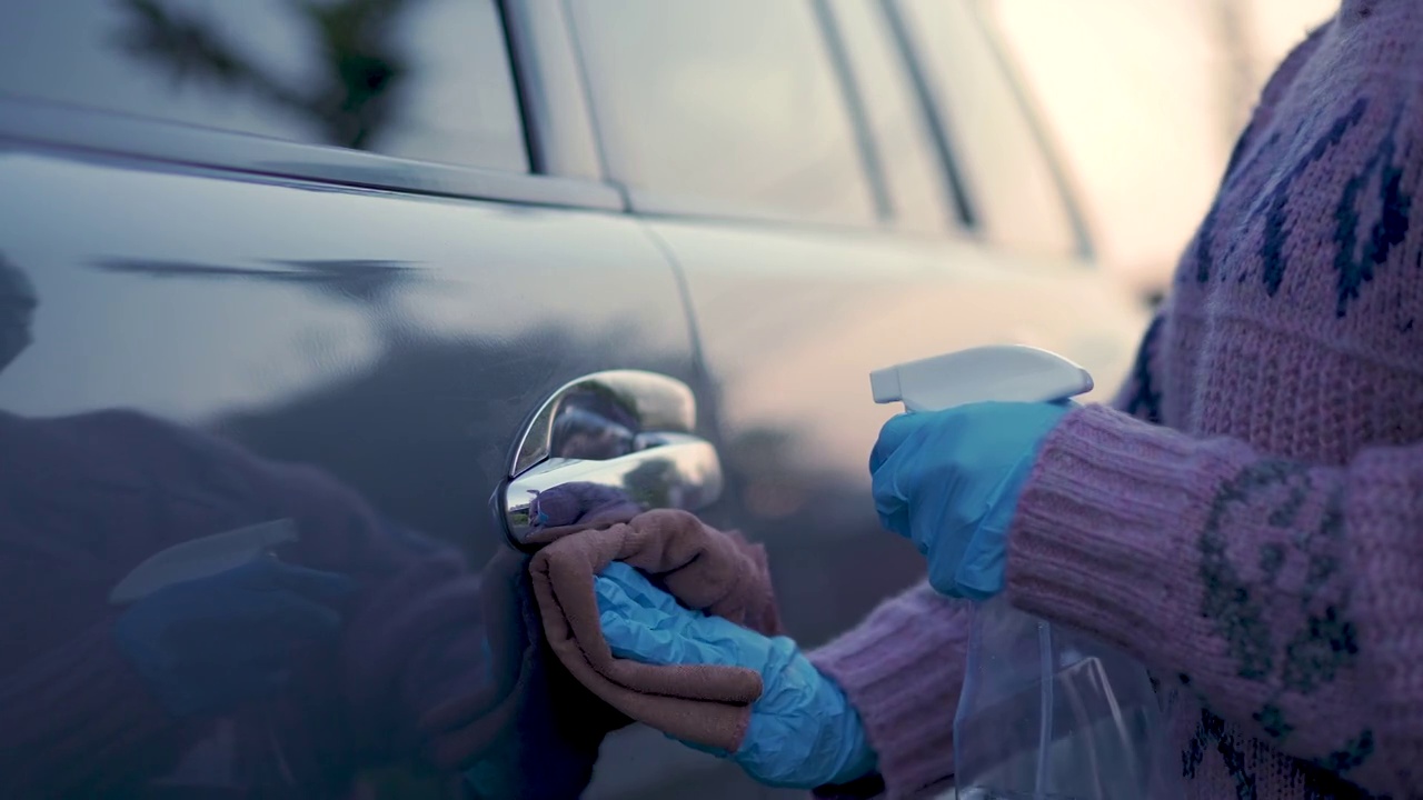 亚洲妇女戴着医用口罩和手套喷洒和擦拭汽车，预防，预防covid - 19冠状病毒大流行感染，洗车，现代生活方式视频素材