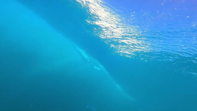 在夏威夷瓦胡岛，水下抬头看汹涌的海浪，海浪在水面上翻滚，反射着明亮的阳光和发光的泡泡视频素材