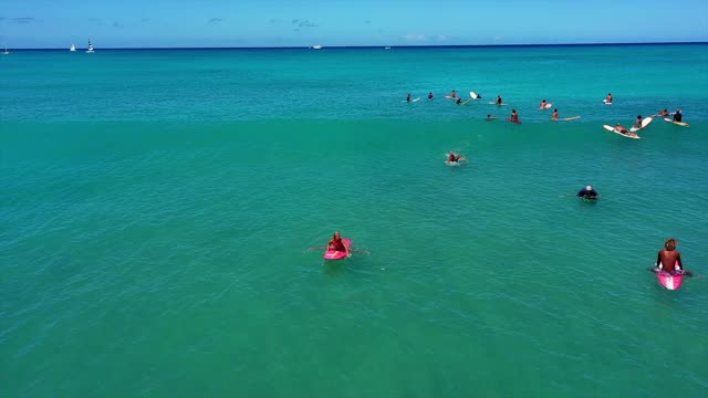 空中拍摄的人冲浪在碧绿的海洋对天空，无人机向后飞行在海浪冲浪者在阳光明媚的一天-瓦胡岛，夏威夷视频素材