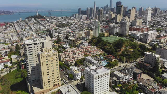 空中平移拍摄的城市由著名的桥在海上对天空，无人机飞过现代城市景观在阳光明媚的一天-旧金山，加利福尼亚视频素材