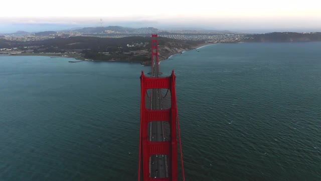 空中倾斜拍摄海湾上的金门大桥上的车辆，日落时分，无人机在著名地标上空向前飞行——加利福尼亚州旧金山视频素材