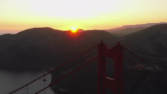 空中平移拍摄受欢迎的金门大桥的山脉对天空，无人机飞过著名的地标日落-旧金山，加利福尼亚州视频素材