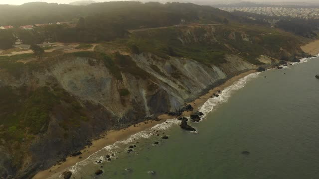 空中摇摄海浪溅在海滩上的悬崖，无人机飞过海岸线-旧金山，加利福尼亚视频素材