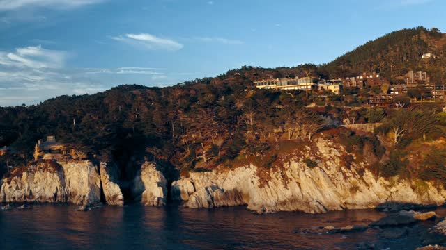 空中摇摄的房子在悬崖上对着天空在日落，无人机飞近岩石海岸线-岩石海岸线在卡梅尔比斯-卡梅尔海边，加利福尼亚视频素材