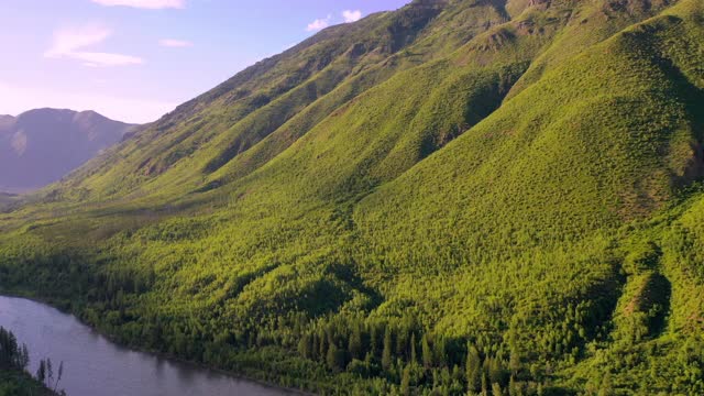 空中摇摄河流流动的绿色山脉对天空，无人机飞过自然景观在阳光明媚的一天-大北方平原，MT视频素材