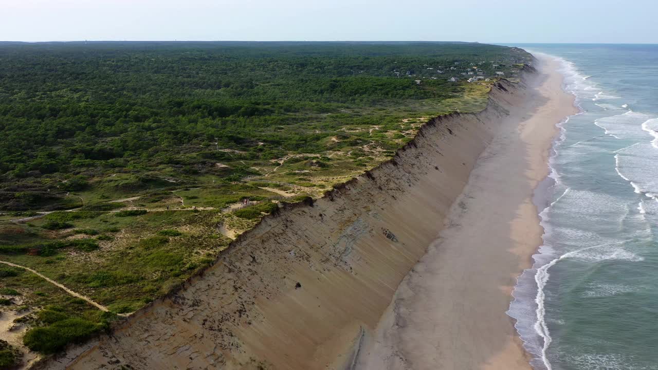 空中平移拍摄海滩沙丘上的植物对天空，无人机飞越海岸线上溅起的波浪-科德角，马萨诸塞州视频素材