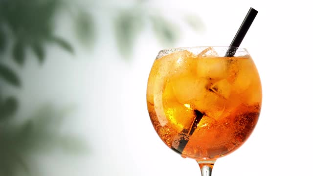 杯aperol喷雾剂鸡尾酒与冰和吸管打开散焦叶子背景视频素材