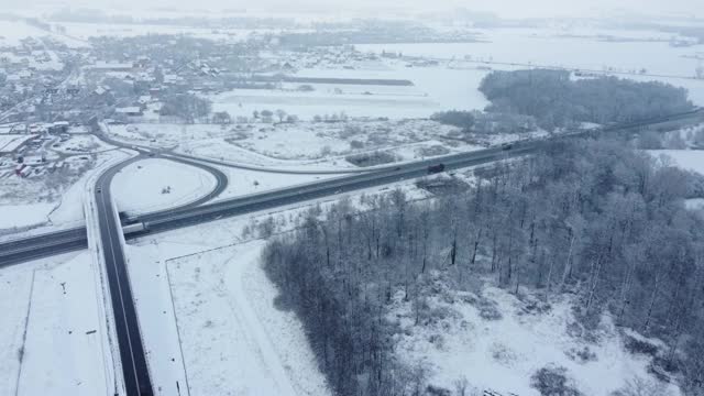 黑色柏油路之间的雪林从鸟瞰。视频素材