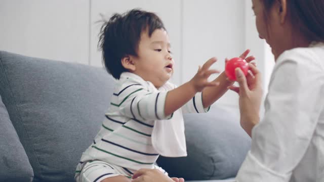 亚洲父母和男婴在家里的客厅玩塑料球视频素材