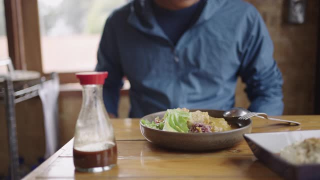 慢莫:年轻的亚洲男子吃豆腐米饭和绿色沙拉。视频素材