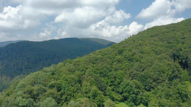 在一个温暖的夏天，山上的绿色森林与多云的天空相映衬。视频素材