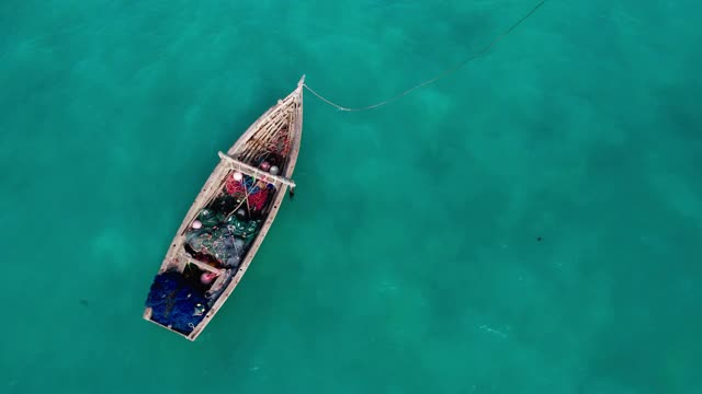 航拍渔民的船漂浮在碧绿的印度洋波浪附近的桑给巴尔岛，坦桑尼亚。从无人机角度观看4K视频。旅游和渔业概念视频。视频素材