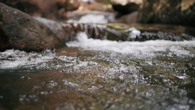 慢动作的野生山河丰富清澈的小溪流过岩石。河流岩石与流水的特写。近距离视频素材