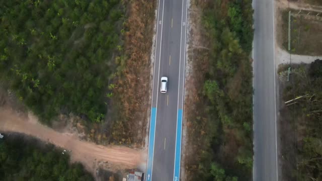 宽阔的无人机镜头跟踪一辆汽车在空旷的道路上被美丽的城外包围。视频素材