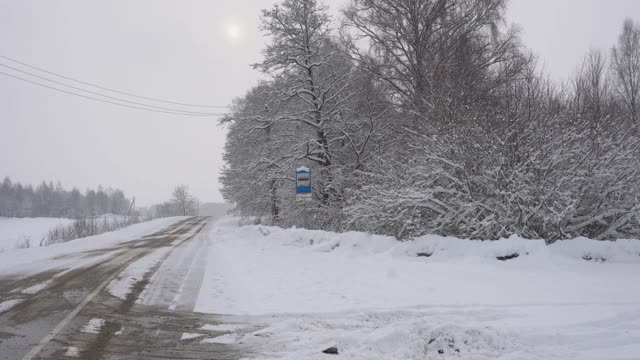 乡间小路穿过一片白雪皑皑的森林，很多雪，树木在雪地里，乡间小路，冬天的故事视频素材