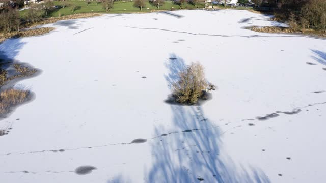 这是苏格兰一个被冰雪覆盖的湖上的一个小岛的鸟瞰图视频素材