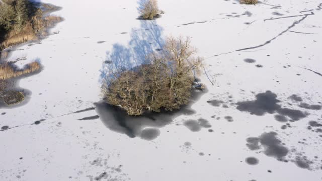 这是苏格兰一个被冰雪覆盖的湖面上的一个小岛的鸟瞰图视频素材