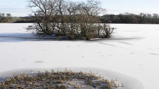 这是苏格兰一个被冰雪覆盖的湖上的一个小岛的无人机照片视频素材