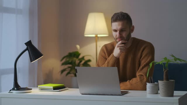 男人正在通过笔记本电脑视频聊天、在线交流和谈判来倾听同事或伙伴的声音视频素材