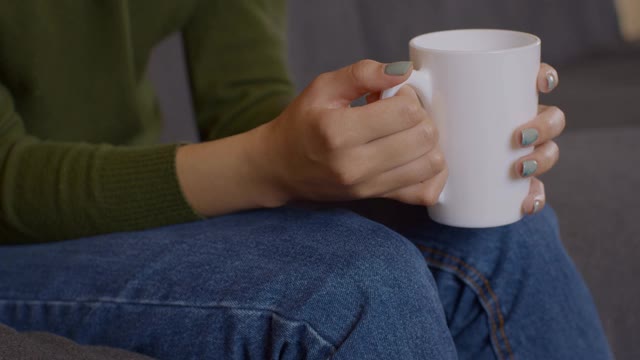 女性手捧一杯热茶的特写镜头，温暖的手掌，慢动作视频素材