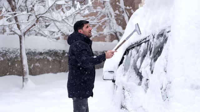 一名男子清理汽车附近的积雪视频素材