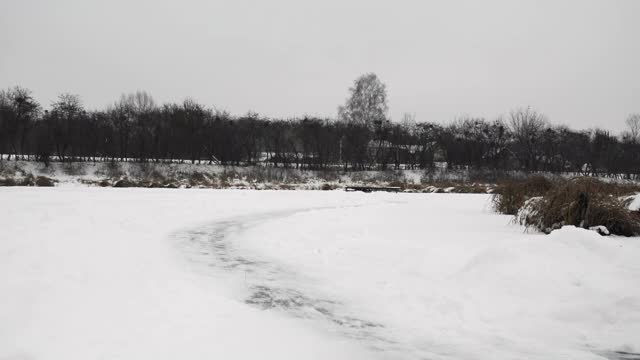 冬天，人们在结冰的湖面上滑冰。室外滑冰。冬季运动活动。在冬天寒冷的日子里，穿着黑色冰鞋的男性在结冰的河流上滑行视频素材