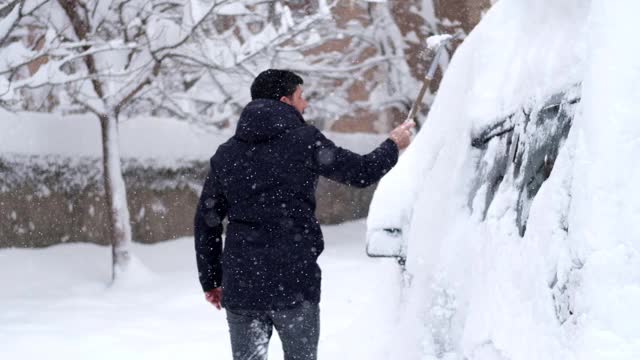 一名男子清理汽车附近的积雪视频素材