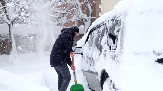 一名男子清理汽车附近的积雪视频素材