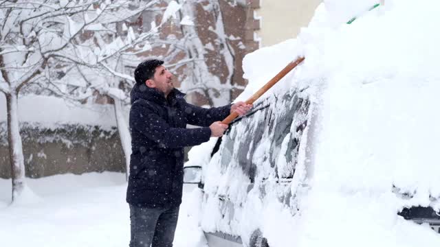 一名男子清理汽车附近的积雪视频素材