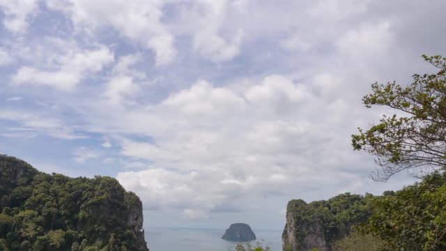 小岛在美丽的巨大的岩石山中间。蓝天和云在山上移动。晴天多云的天空。b - roll间隔拍摄的镜头。泰国南部海滩的探险之旅。视频素材