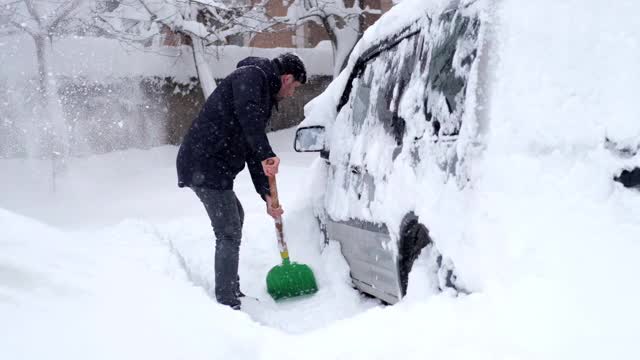 一名男子清理汽车附近的积雪视频素材