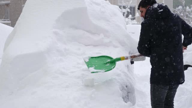 一名男子清理汽车附近的积雪视频素材