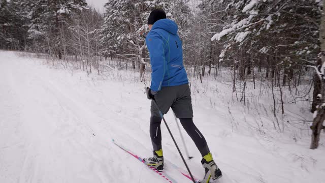 体育生活方式。一个男人在冬季森林里越野滑雪。准备视频素材