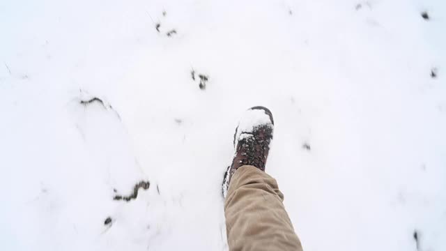 自己的视角的人走在雪地上在农村徒步鞋。视频素材