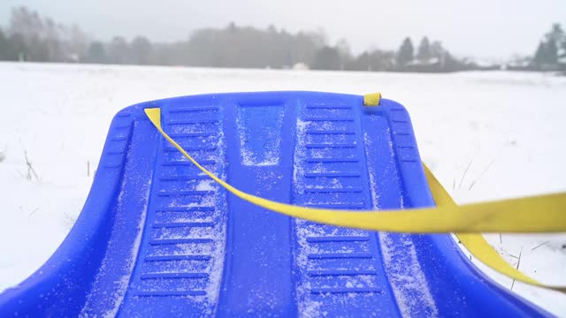 一个人在雪地上拉着雪橇，背景是一片松树林。视频素材