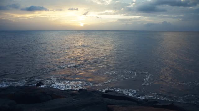 美丽的日出——太阳照耀着海水，撞击着岩石海岸。视频素材