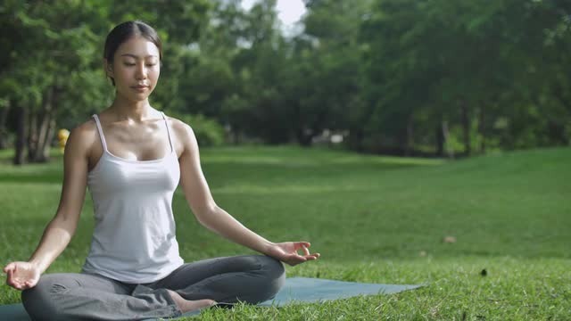 年轻的亚洲女性在公园里练习瑜伽视频素材