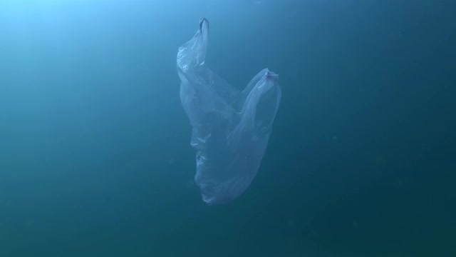 慢镜头，蓝色的塑料袋在蓝色的水面下慢慢漂浮。水下塑料污染海洋。塑料垃圾环境污染问题视频素材