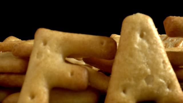 FAT这个词是用饼干写的。不健康饮食和过量盐摄入量的概念。靠近黑色桌子上的饼干。视频素材