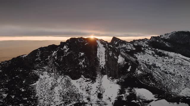 鸟瞰图的山峰在冬季日落。雪山和橙色的云在背景。高质量4k镜头视频素材