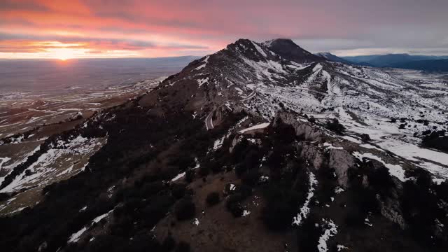 鸟瞰日落时白雪覆盖的高山。高质量4k镜头视频素材