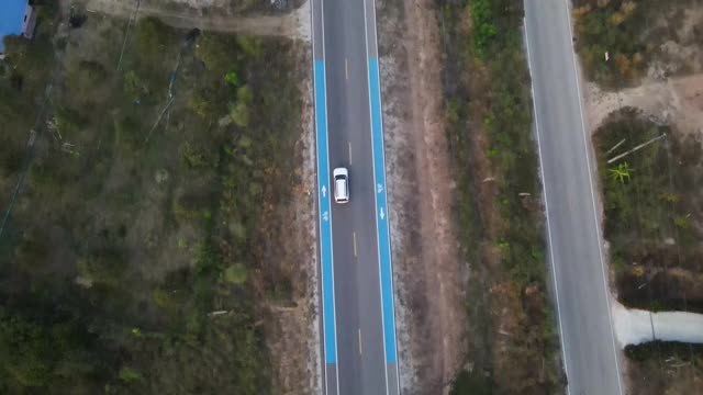 宽阔的无人机镜头跟踪一辆汽车在空旷的道路上被美丽的城外包围。视频素材