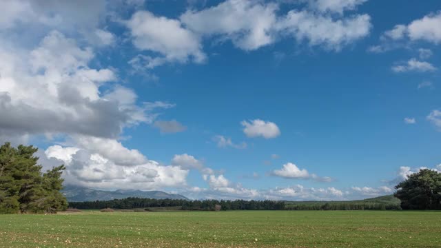 一个多云的天空与彩虹在树和空旷的田野上的时间流逝视频视频素材